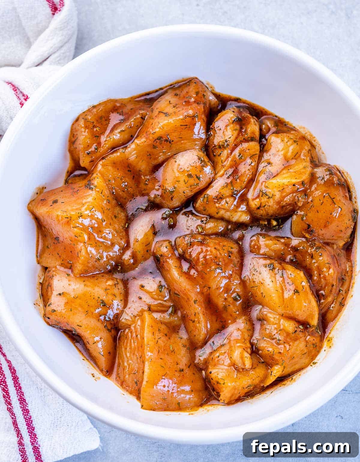 Chicken pieces marinating in a white bowl, coated in a rich, savory sauce.