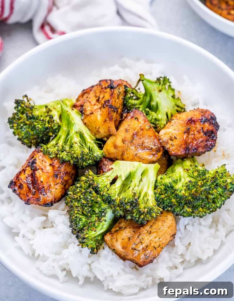 Top view of a round plate of fluffy rice, generously topped with air-fried chicken bites and vibrant broccoli florets, creating an inviting and healthy meal.