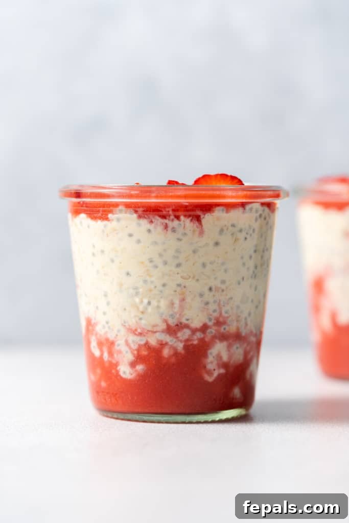 Layers of strawberry puree with overnight oats in a jar.