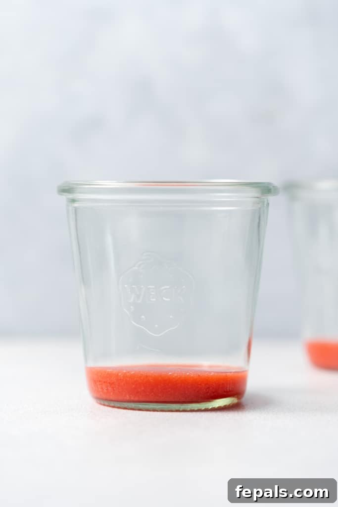 Adding strawberry puree to a jar.