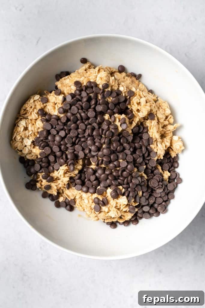 Chocolate chips sitting on top of the oat peanut butter mixture, ready to be folded in.