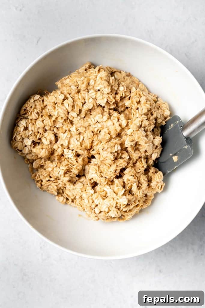 Oats fully mixed with peanut butter and honey, forming a sticky, cohesive mixture.