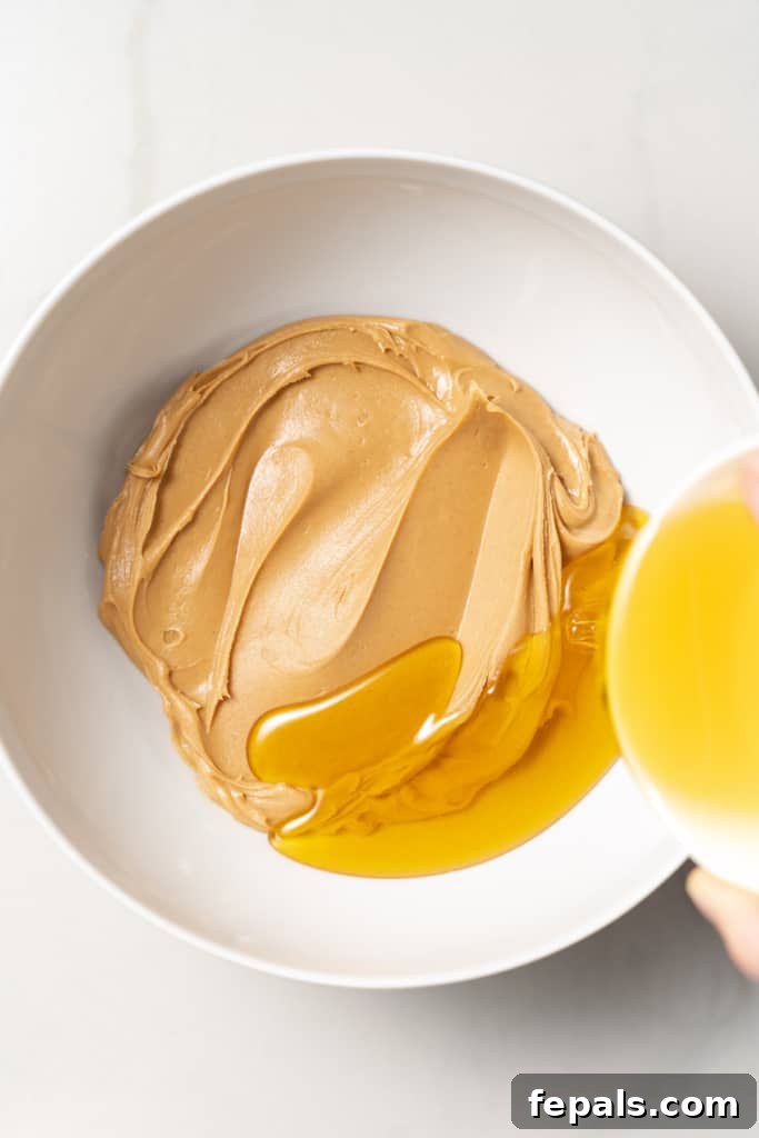 Pouring honey into a bowl with peanut butter.