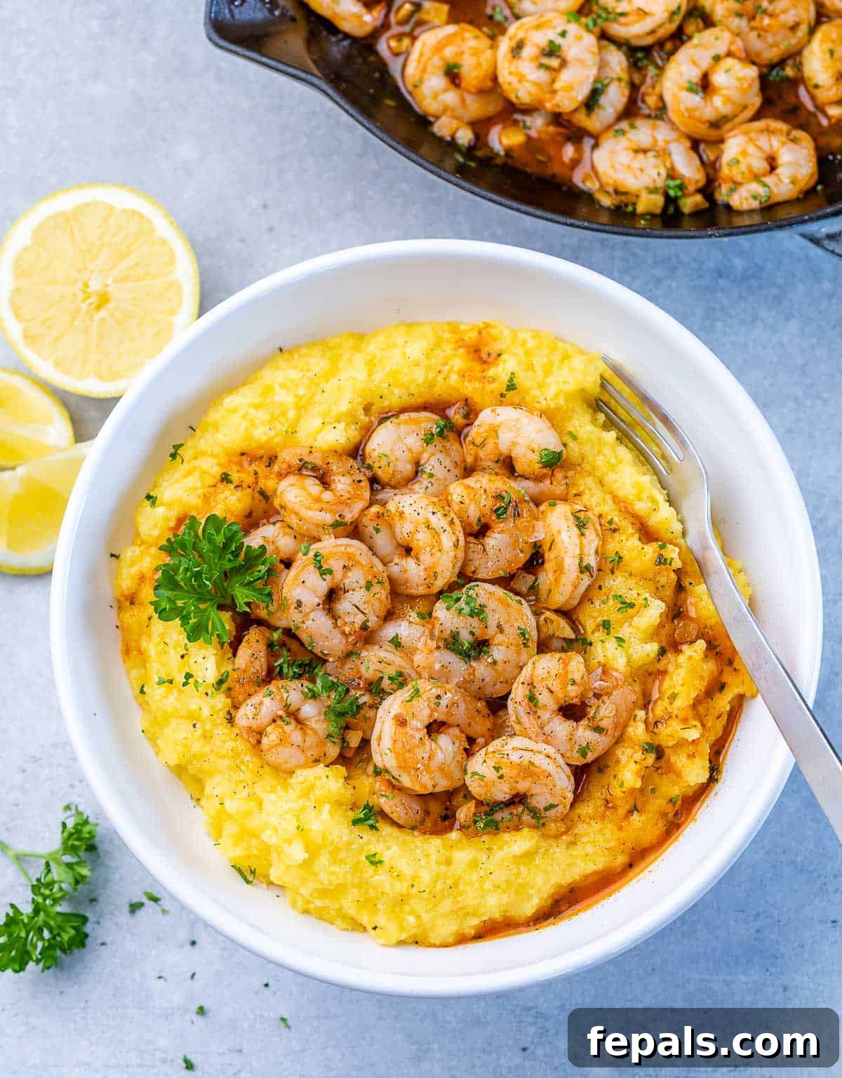 Golden Grits and Gulf Delights 2 Top view of yellow grits in a round white plate topped with sautéed shrimp.