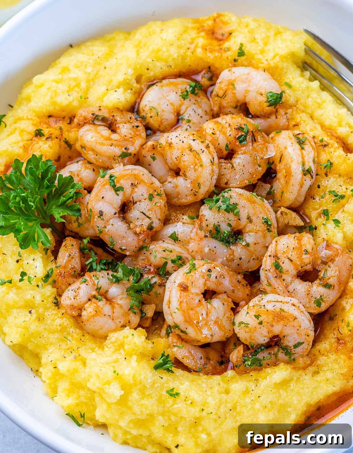 Golden Grits and Gulf Delights 3 Closeup view of Shrimp and Grits garnished with fresh parsley.