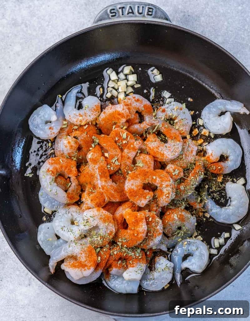 Golden Grits and Gulf Delights 7 Adding shrimp and seasonings to a pan with sautéing garlic.
