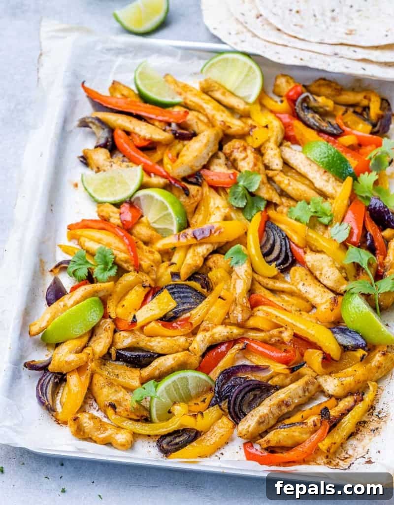 Sheet pan chicken fajitas on a pan with lime wedges.