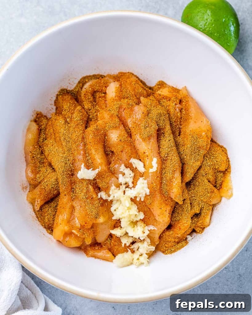 Marinating strips of chicken breast in a white bowl.