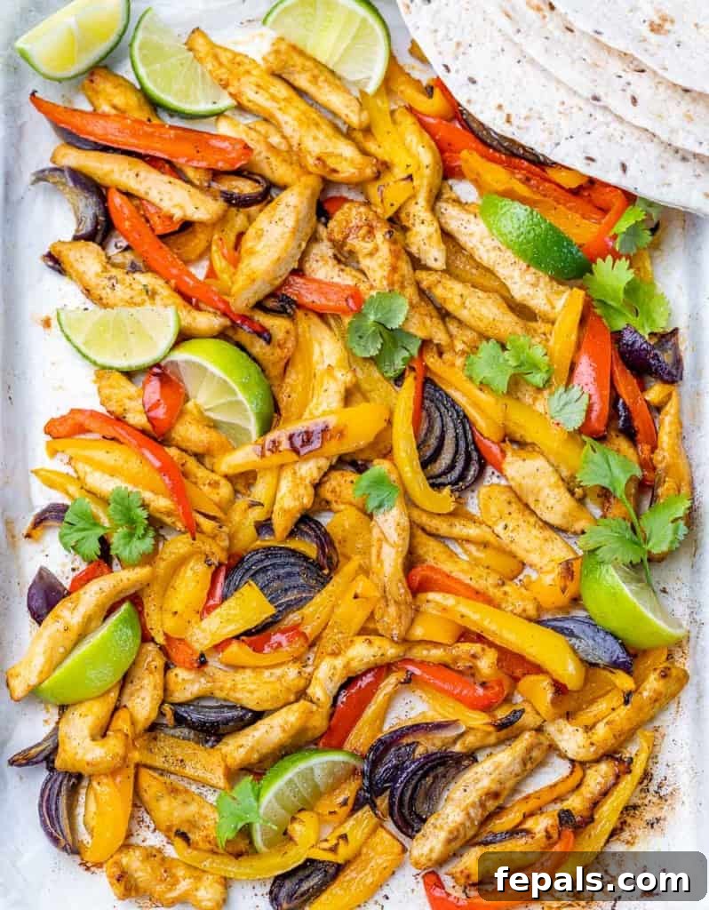 Chicken fajitas cooked on a parchment-lined sheet pan.