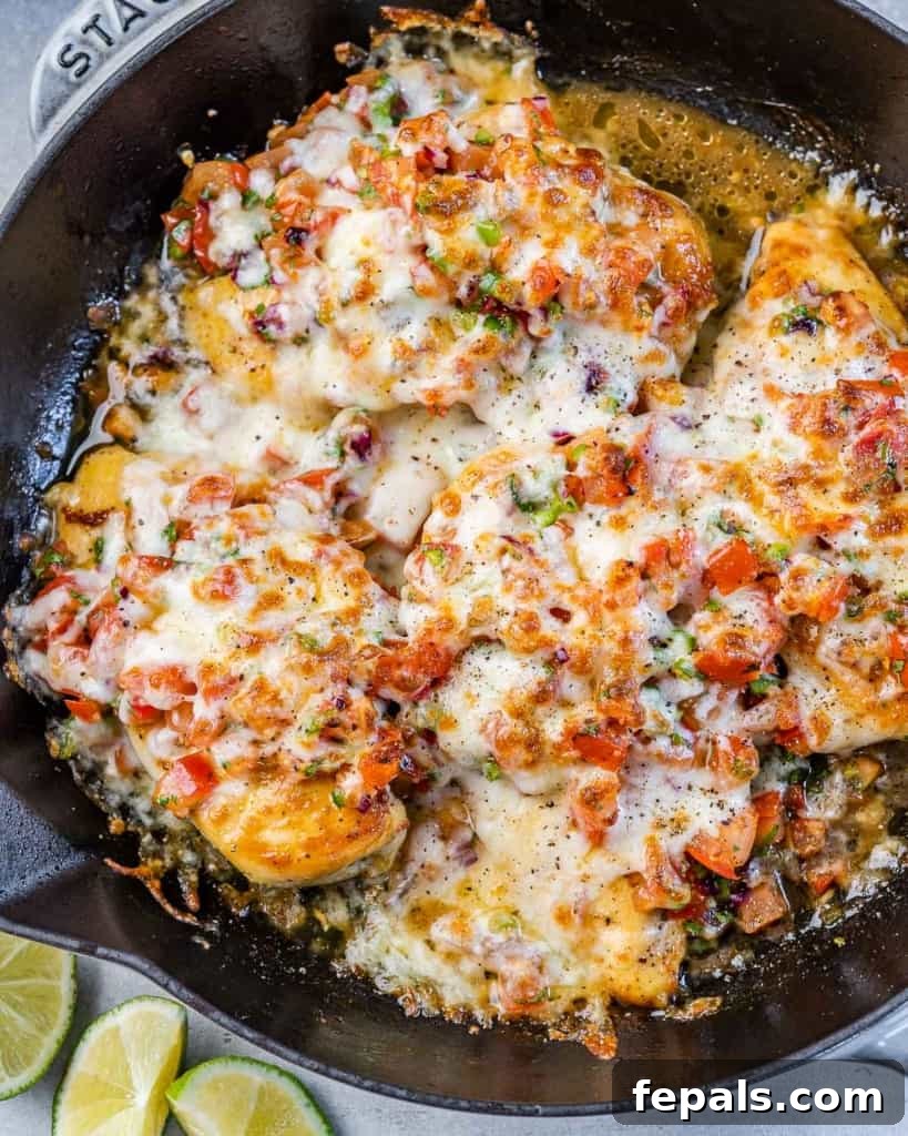 Zesty Salsa Fresca Chicken Bake 3 close up view of a black skillet with baked chicken breast topped with salsa fresca and melted cheese