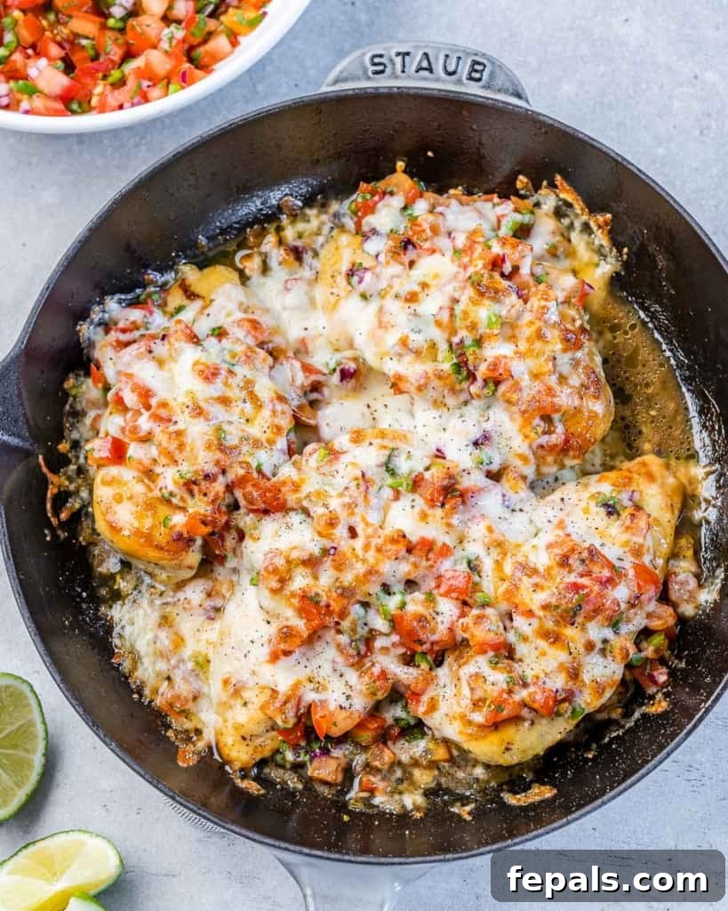 Zesty Salsa Fresca Chicken Bake 8 top view baked chicken breast on a black skillet topped with salsa and melted cheese