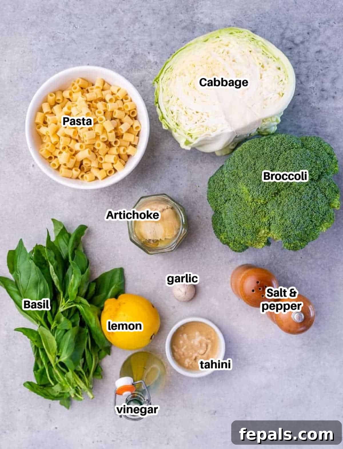 Zesty Green Goddess Pasta Salad 4 Ingredients laid out to make green goddess salad with pasta, including fresh basil, lemon, garlic, tahini, and vegetables.