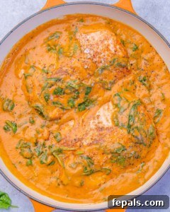 Overhead shot of salmon cooking in a thick spinach and roasted red pepper sauce.