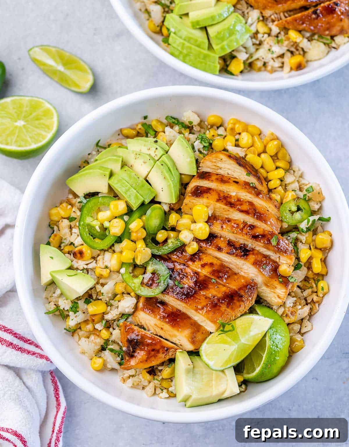 Smoky Chipotle Chicken Rice Bowl 2 Top view bowl with cauliflower rice topped with sliced grilled chicken breast with corn avocado and sliced jalapeño.
