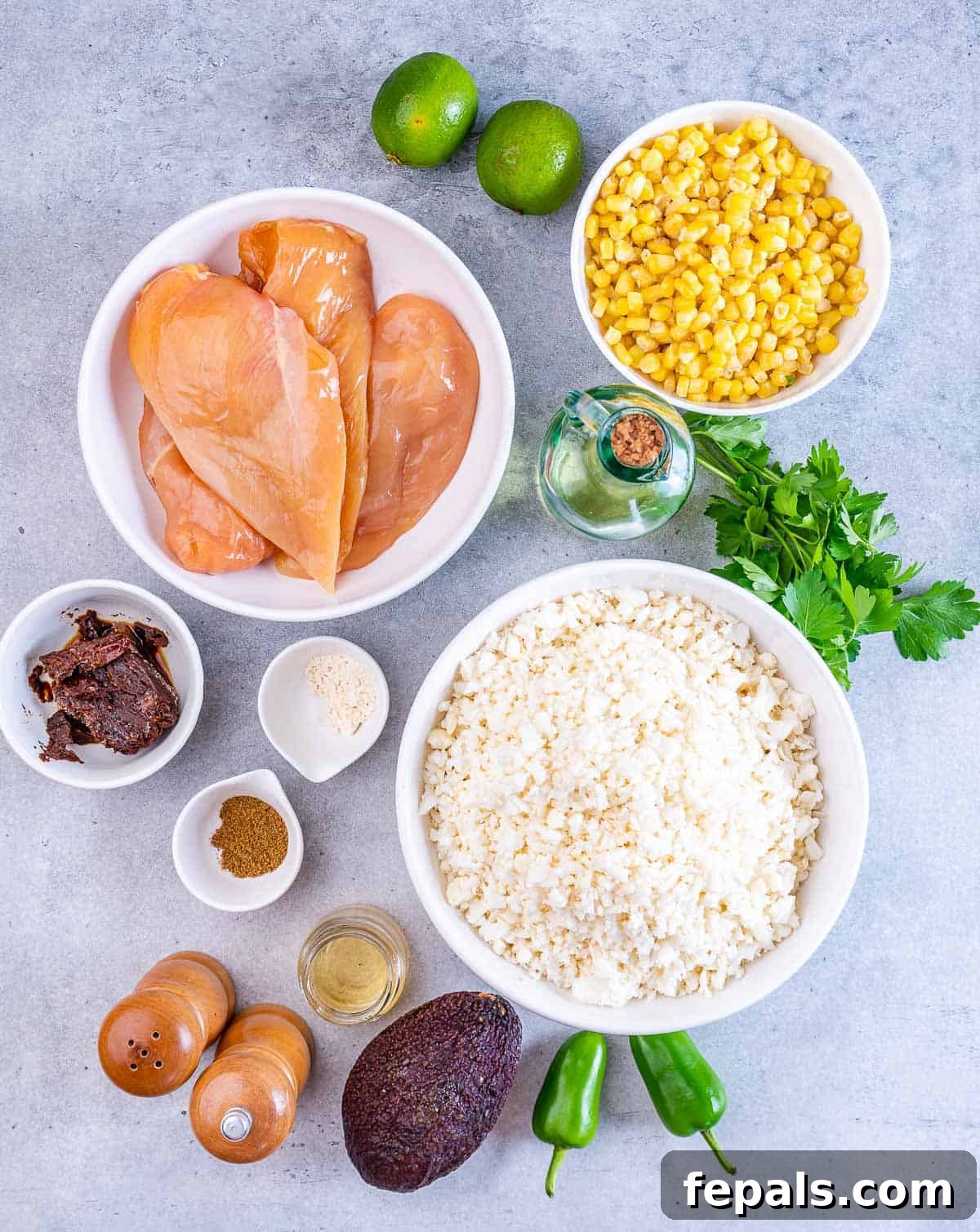 Smoky Chipotle Chicken Rice Bowl 4 Raw chicken in a bowl near bowls of corn, cauliflower rice, chipotle peppers and seasonings.