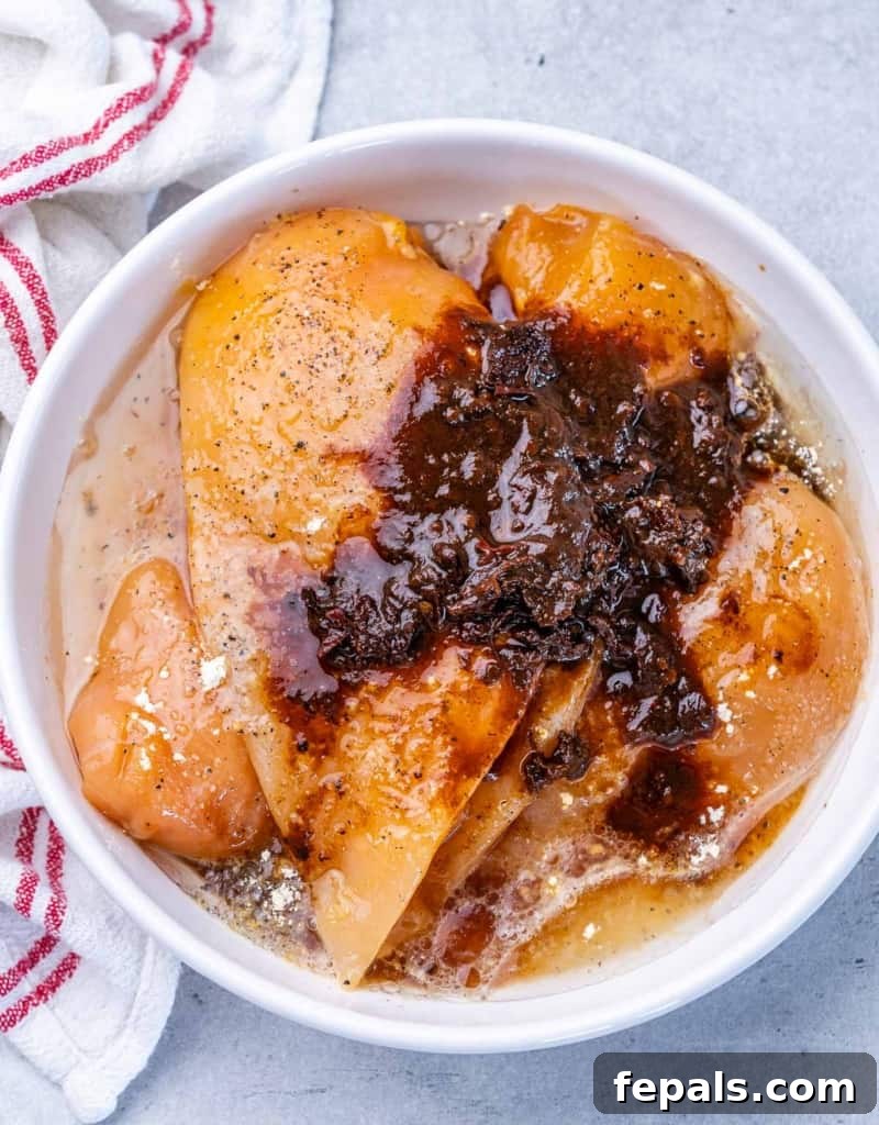 Smoky Chipotle Chicken Rice Bowl 5 Chicken breasts marinating with chipotle chiles, lime juice and honey in a white bowl.