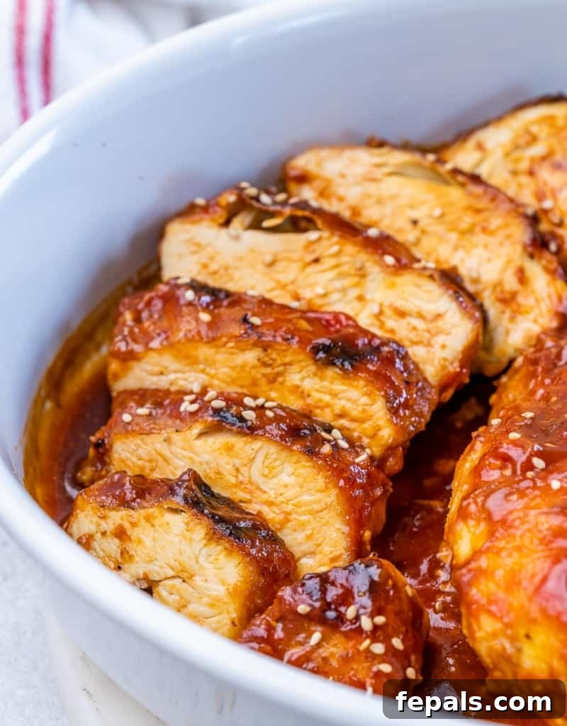 Sticky Honey Sriracha Chicken 10 Side shot of perfectly sliced baked chicken breast in a white dish, showing its juicy interior.