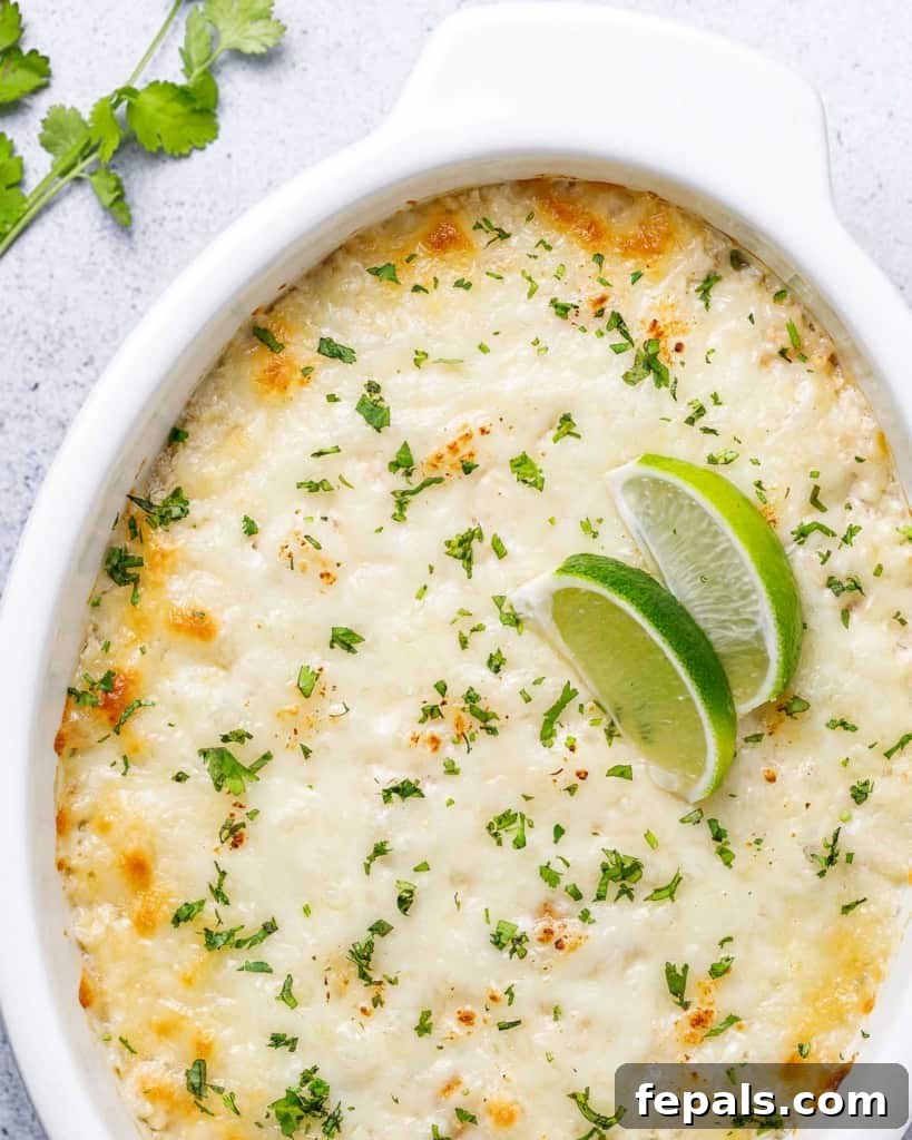 Close-up top view of a white dish filled with a bubbly, golden-brown cheese chicken and cauliflower rice casserole, highlighting the rich texture.