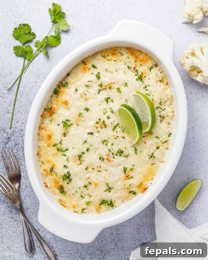 Top view of a freshly baked chicken and cauliflower rice casserole in a white dish, garnished with two bright green lime wedges, ready to be enjoyed.