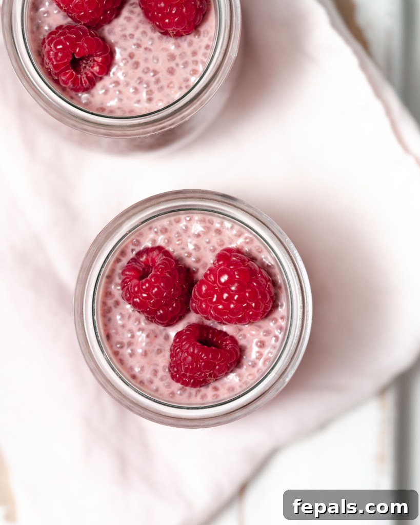 top view of chia pudding in a jar topped with three fresh raspberries, ready to be enjoyed