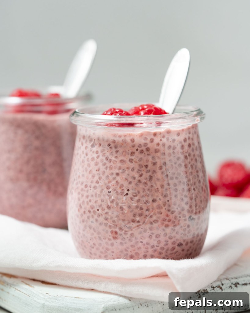 side shot of chia pudding in a jar that's pink in color with a spoon in the jar, ready to be eaten