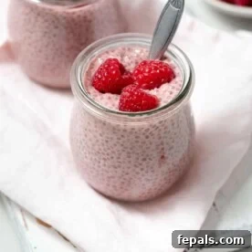a jar of raspberry chia pudding topped with fresh raspberry.