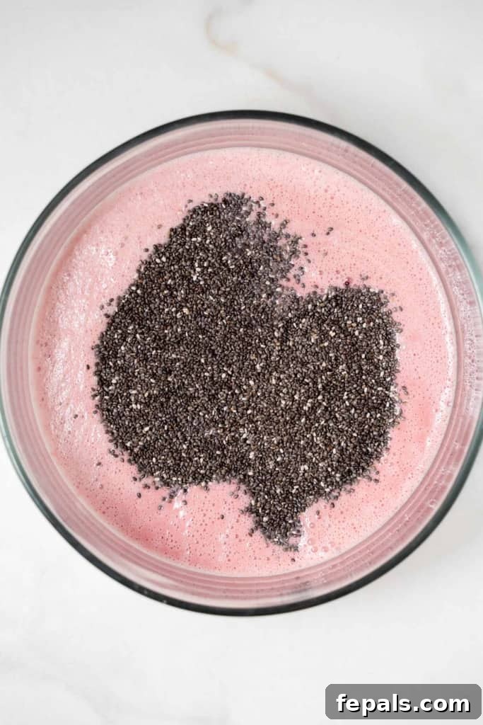 chia seed added over blended raspberry and milk in a bowl