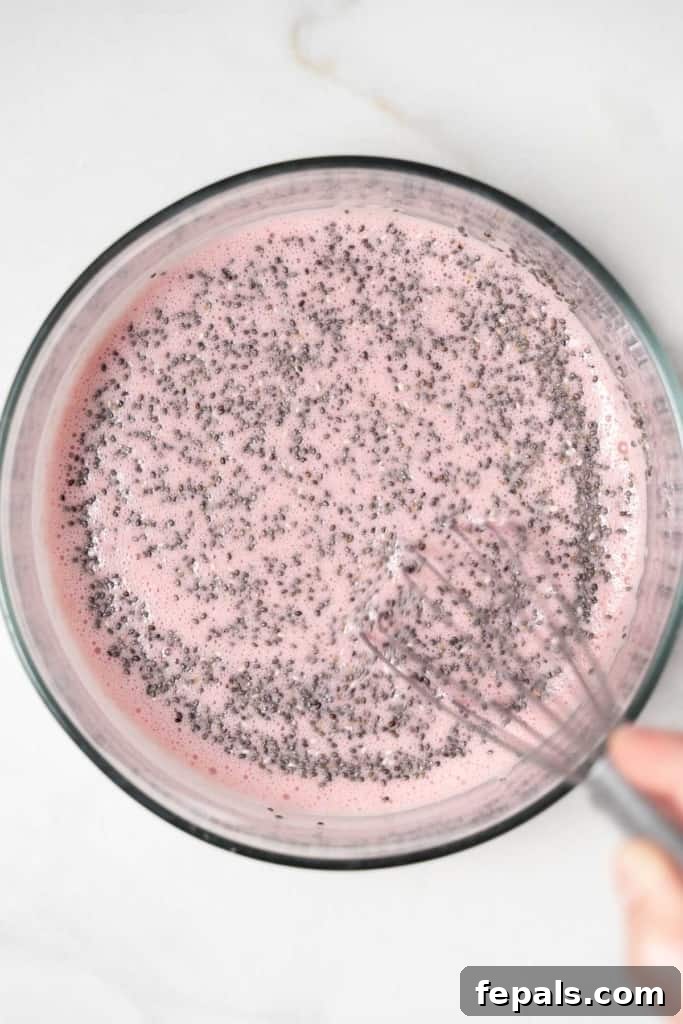 hand whisking chia seed with the raspberry blended milk until combined