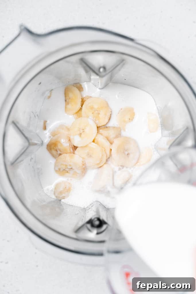 Nutty Banana Bliss Smoothie 5 Pouring milk into blender with banana slices.