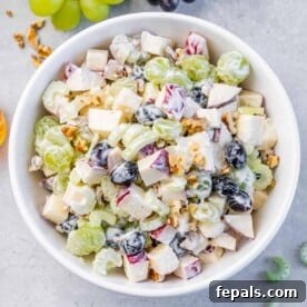 Top view salad with fruits and nuts in a round bowl.