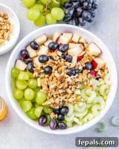 Grapes, celery, apples and walnuts in a white bowl.