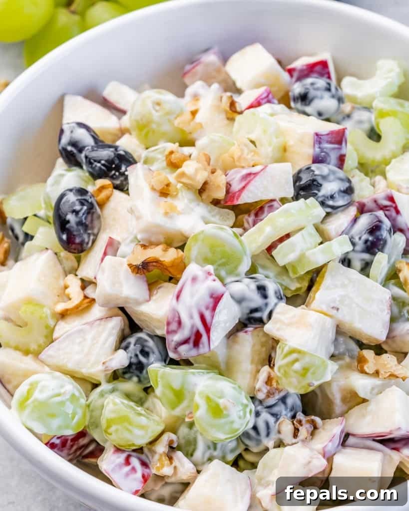 Waldorf salad with green and red grapes in a white bowl, ready to be served.