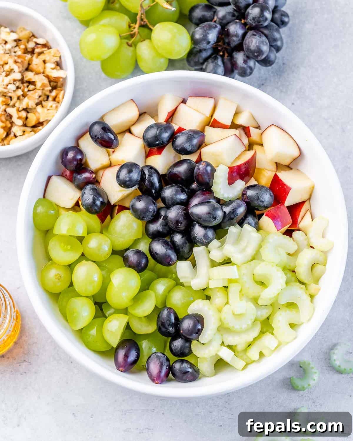 Chopped grapes, celery, and apples mixed together in a white bowl.
