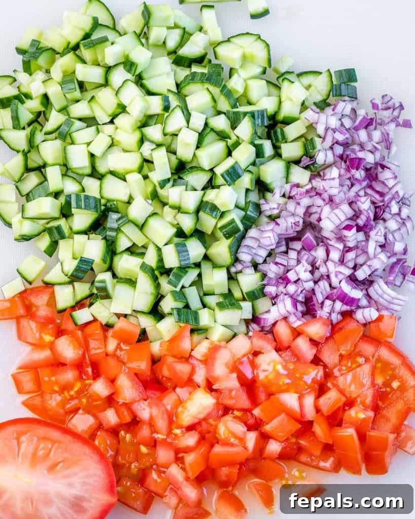 Refreshing Persian Shirazi Salad 5 Finely chopped cucumber, red onion, and tomato pieces on a wooden cutting board, ready for the salad bowl.