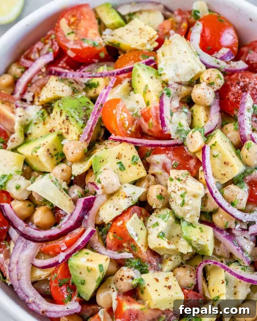 Closeup of a Mediterranean Artichoke and Tomato Salad tossed with tender artichokes, vibrant red onion, and creamy avocado.