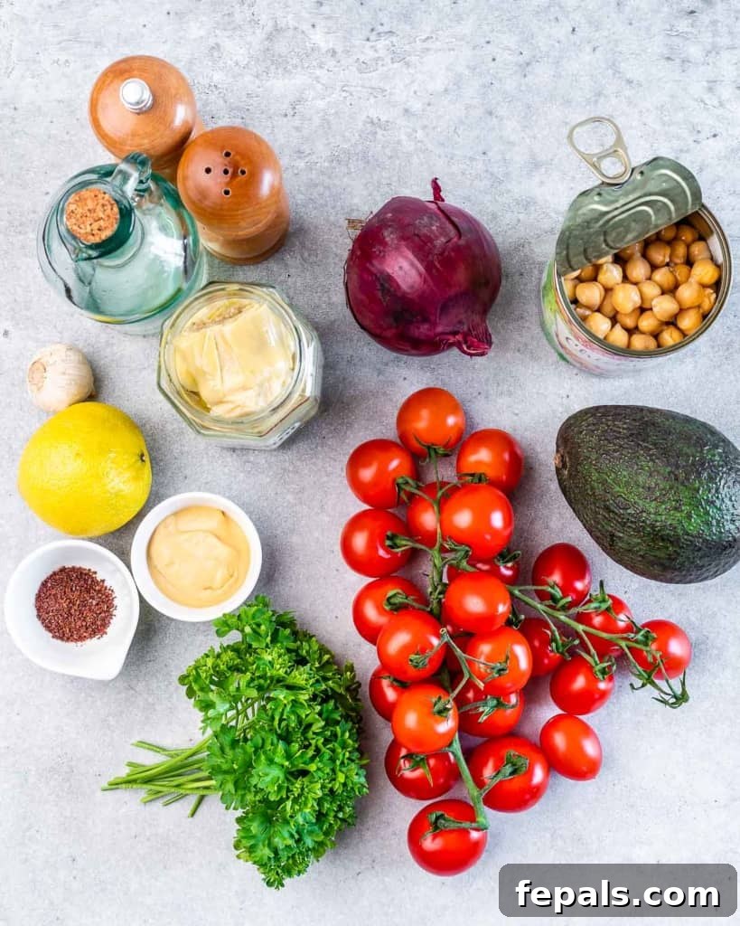 Fresh cherry tomatoes, vibrant parsley, thinly sliced red onion, wholesome chickpeas, and creamy avocado divided into portions, ready for assembly.