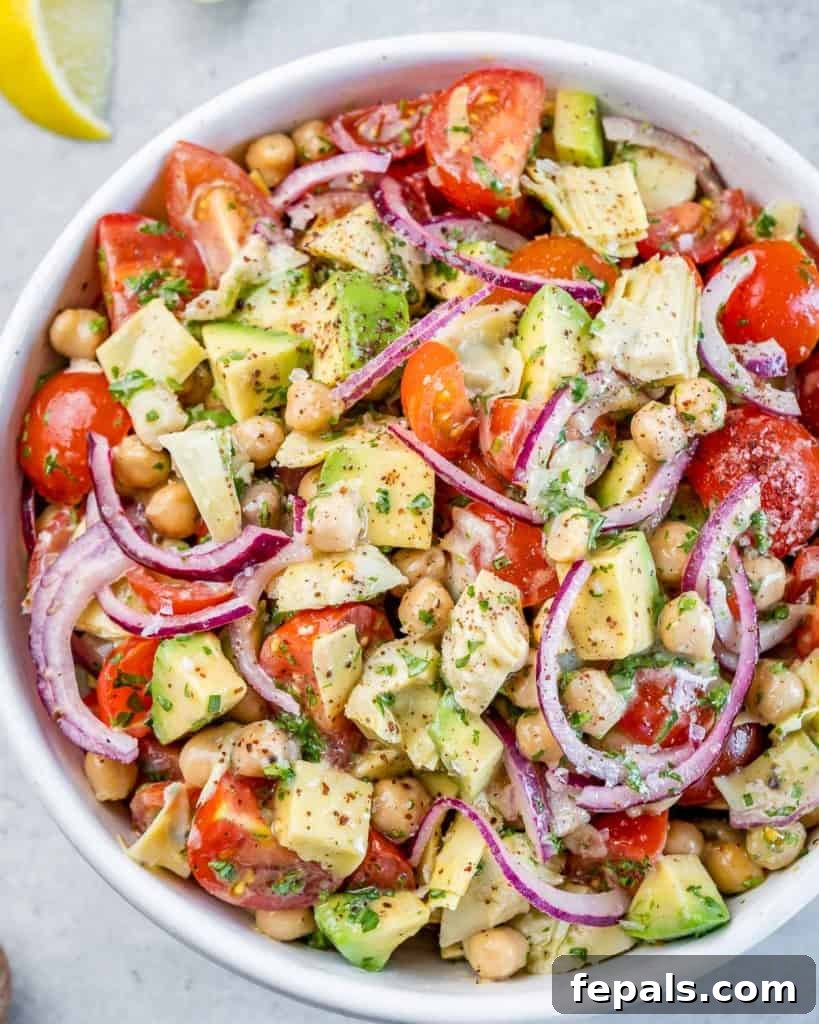 A perfectly dressed Mediterranean salad made with tender artichokes, ripe tomatoes, and creamy avocado, ready to be served.