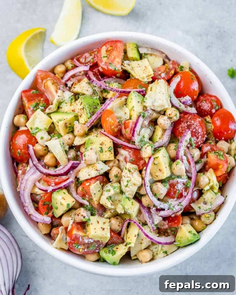 Top view of a beautifully arranged Mediterranean Artichoke and Tomato Salad in a crisp white round bowl, showcasing its vibrant colors and textures.
