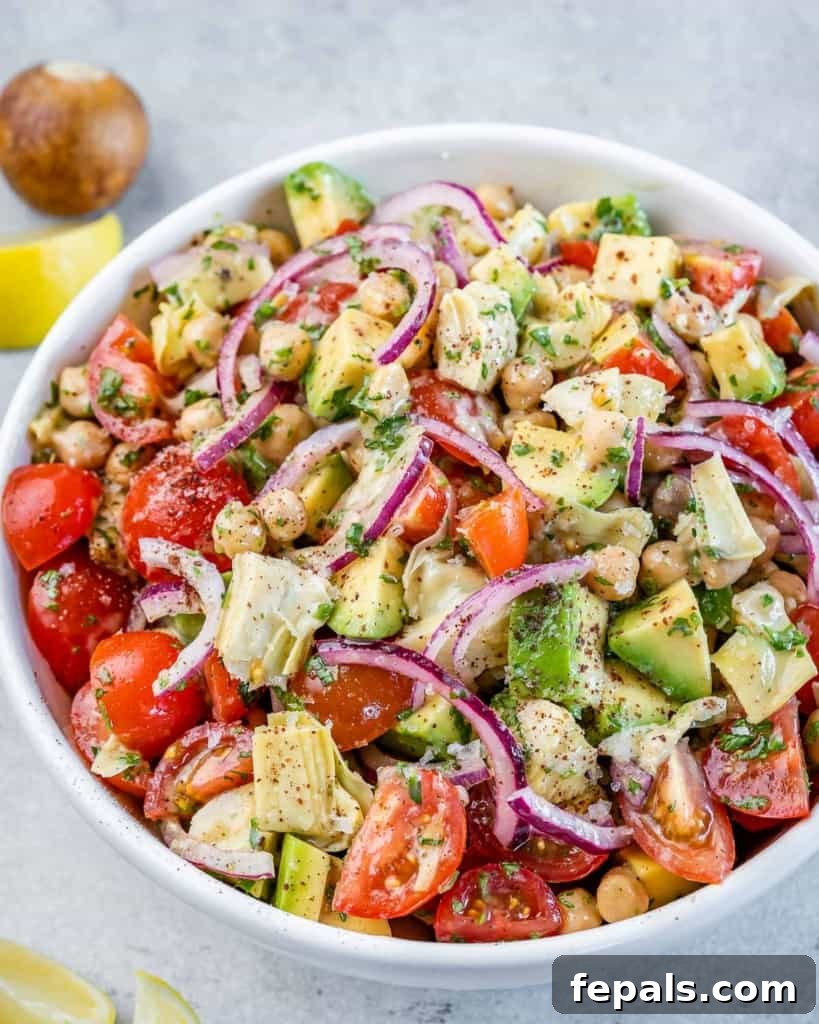 A vibrant Mediterranean Artichoke and Tomato Salad presented in a pristine white serving bowl, showcasing its fresh ingredients and inviting colors.