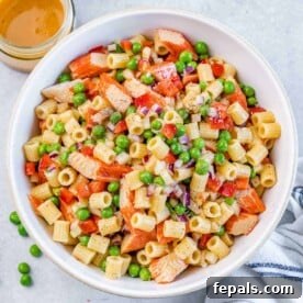 pasta salad with peas and crab in a round white bowl.
