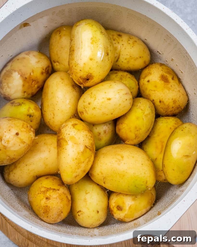 Potatoes boiling in a large pot on a stovetop, capturing the initial cooking phase.