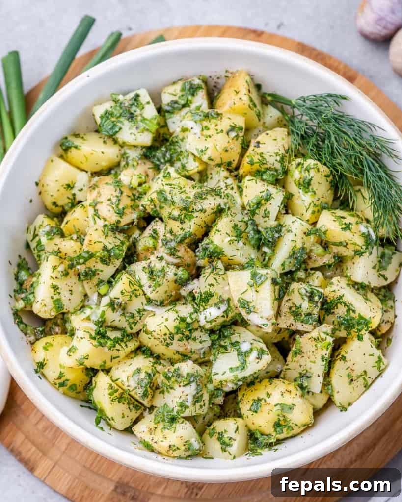 A beautifully presented herbed potato salad in a clean white serving bowl, garnished with fresh herbs, ready for any occasion.