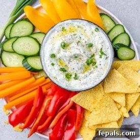 Top view of a plate with veggies and a bowl of whipped cottage cheese with herbs in the middle.