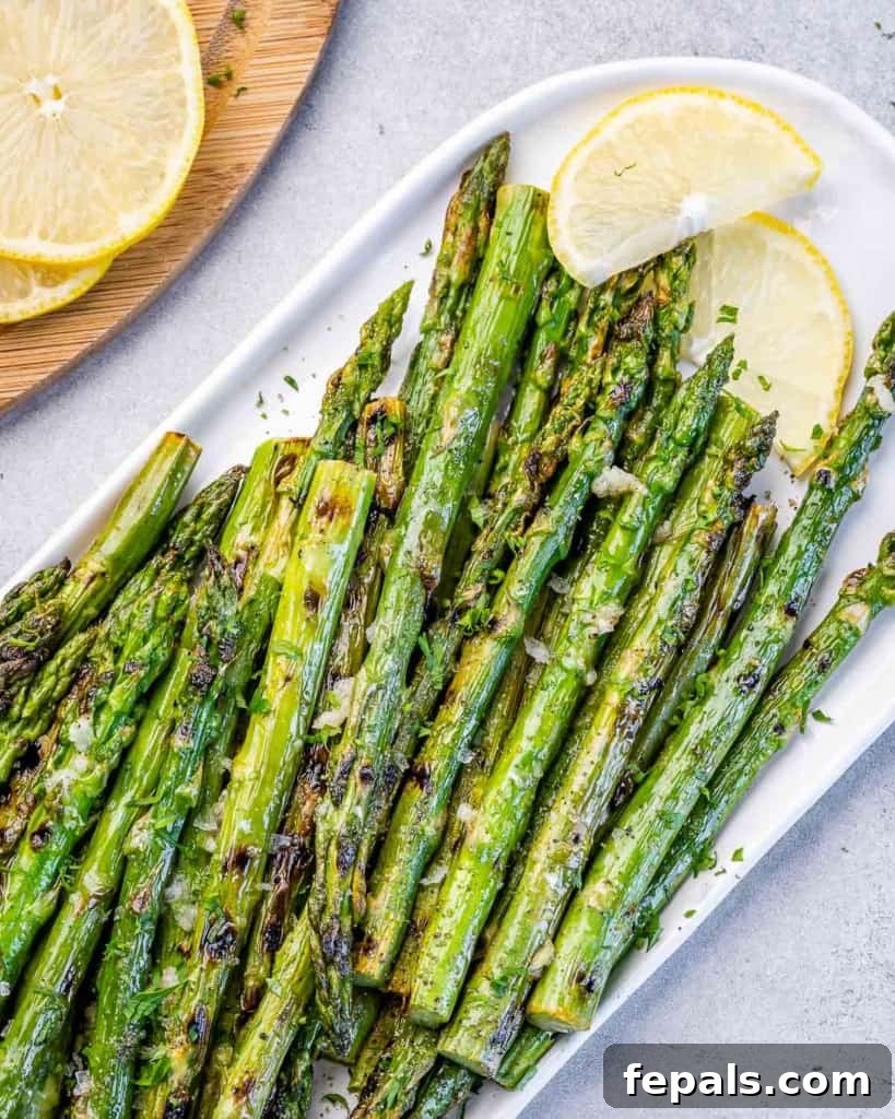 Charred Asparagus with Zesty Lemon-Garlic 8 Grilled asparagus served with lemon wedges on a white tray.
