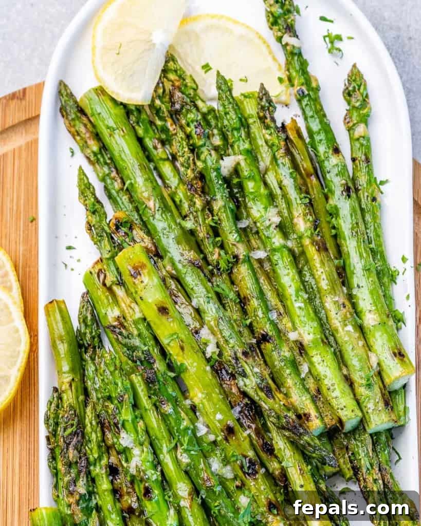 Charred Asparagus with Zesty Lemon-Garlic 9 Top view of grilled asparagus on a plate with lemon wedges on top side.