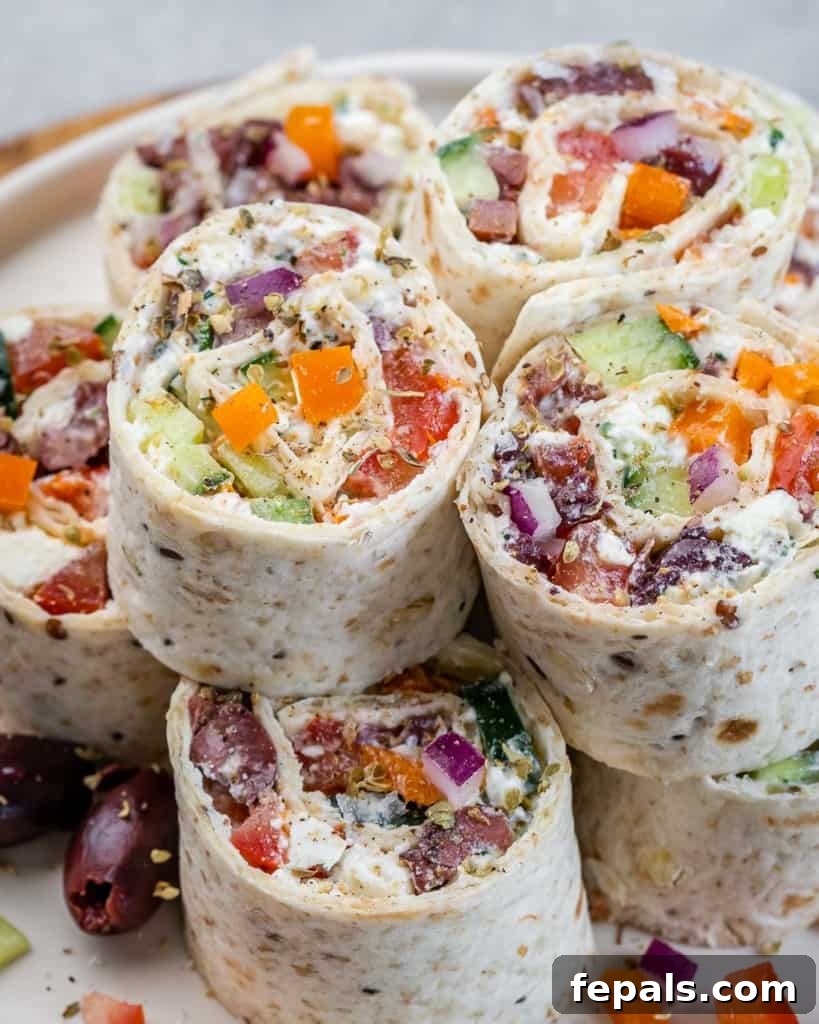 Savory Vegetable Spirals 3 Close-up side view of several Veggie Pinwheel rolls stacked neatly on a white plate, showcasing the vibrant layers.