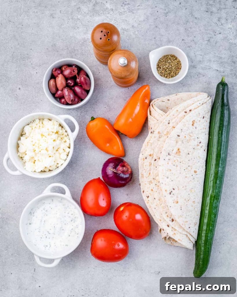 Savory Vegetable Spirals 4 A selection of fresh ingredients laid out on a cutting board, including tzatziki, feta, cucumber, tomatoes, peppers, onions, olives, and tortillas, ready to make veggie pinwheels.