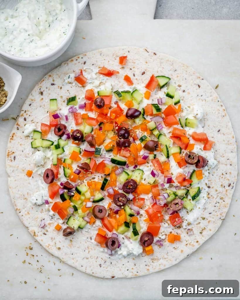 Savory Vegetable Spirals 7 A tortilla covered with creamy spread and a colorful layer of chopped vegetables, ready to be rolled.