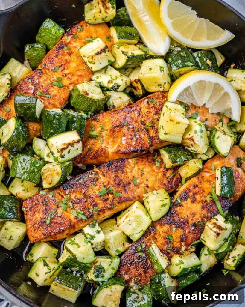 Effortless Cajun Baked Salmon 11 Close-up of a baked salmon fillet with chopped zucchini and a lemon slice garnish, ready to be served.