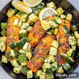 Top view baked salmon with chopped zucchini on a black skillet